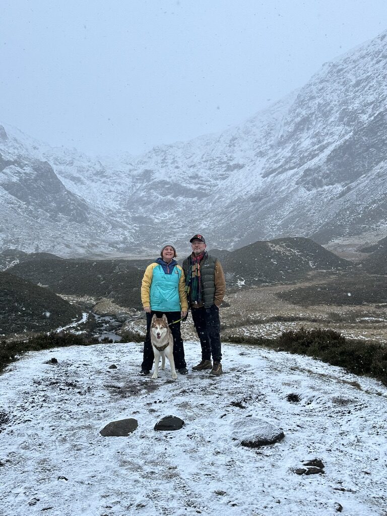 Christine and her husband with Blue the husky on a snowy Scottish hillside